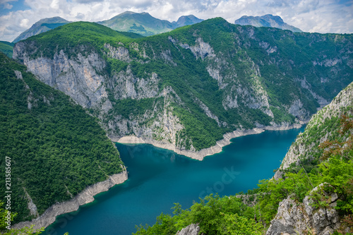 A picturesque turquoise lake can be seen from the top of a high mountain.