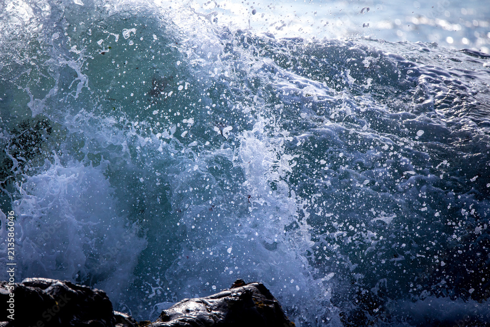 White foamy waves crash and break onto the rocky coastline