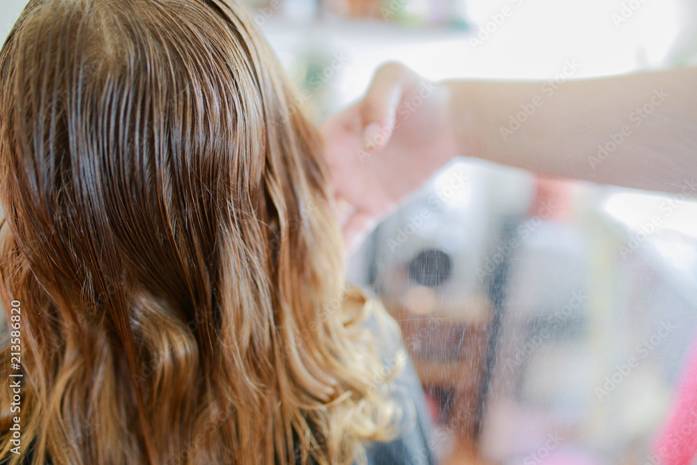 Naklejka premium Cute little blonde curly girl at the beauty salon.