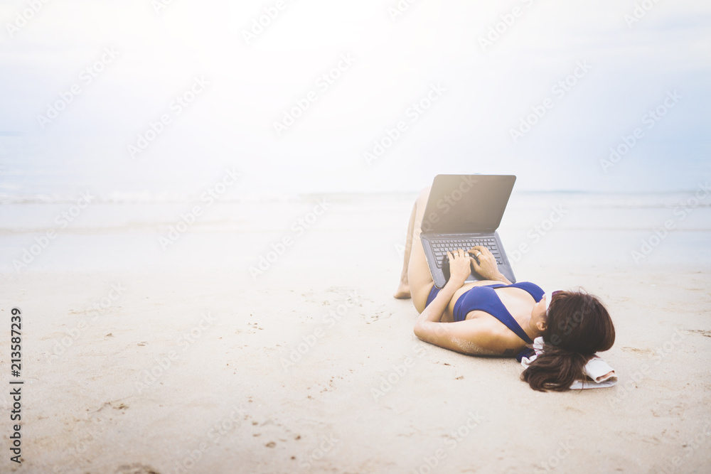 A asia women lying on the beach for working...