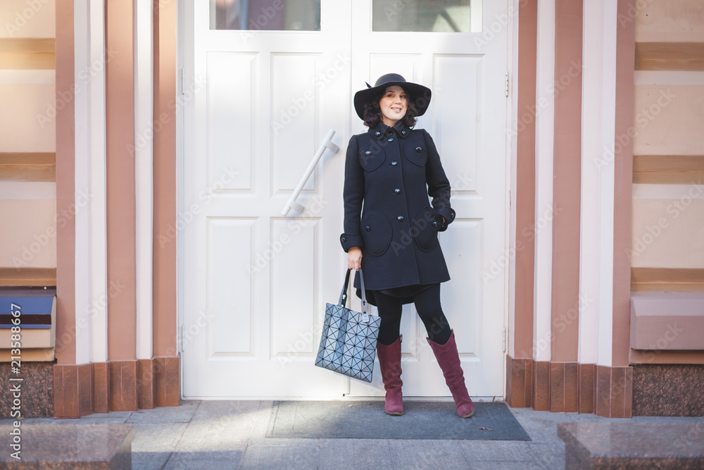 Fototapeta premium Cheerful young woman in a coat and hat.