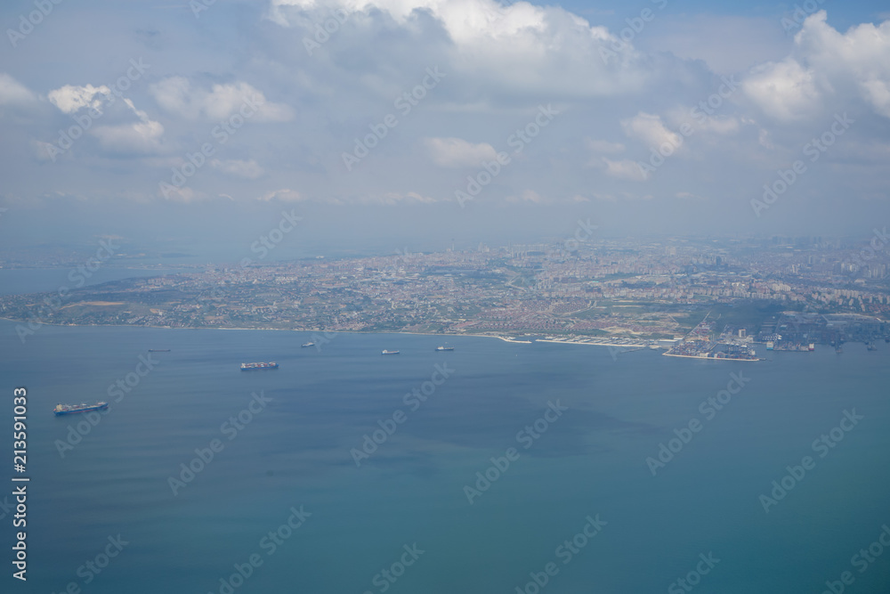 Aerial photo from airplane showing Istanbul cityscape with sea, coast, ships, buildings and sky background