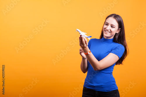 traveler woman play with airplane toy in studio over yellwo background
