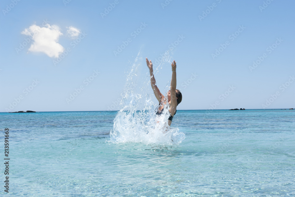 Woman enjoys cool sea water and splashing, summer in Greece