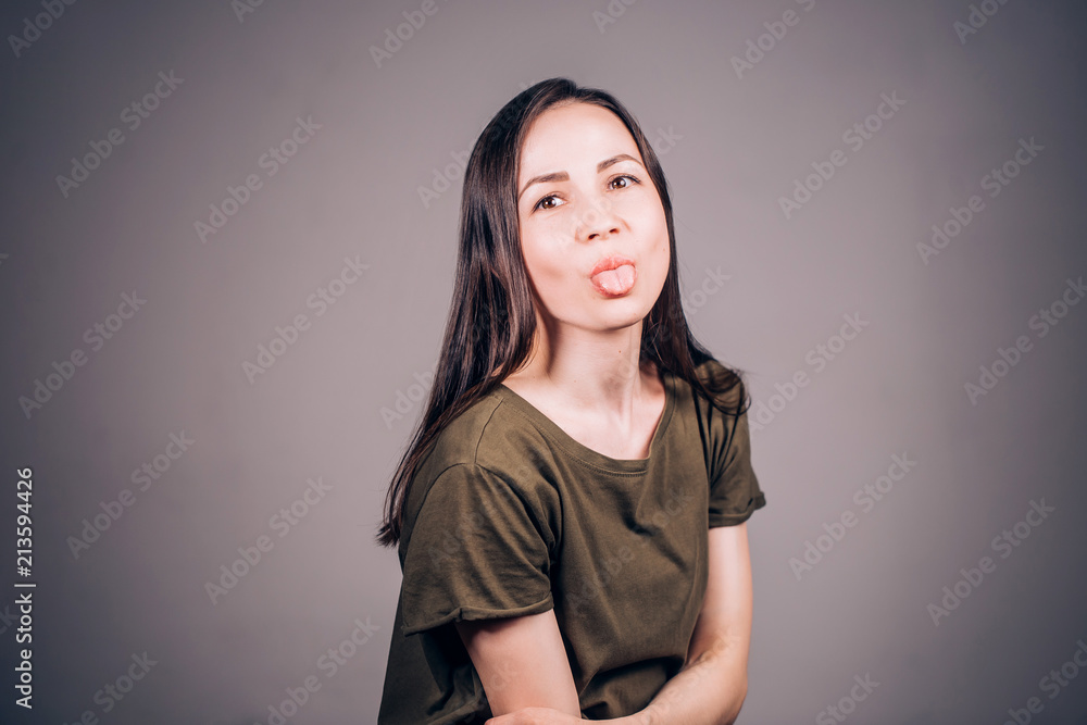 Emotional young beautiful woman shows tongue and looks at camera Emotional young beautiful woman shows tongue and looks at camera