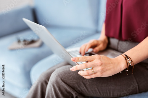 Modern laptop. Careful experienced businesswoman holding a laptop and working with it