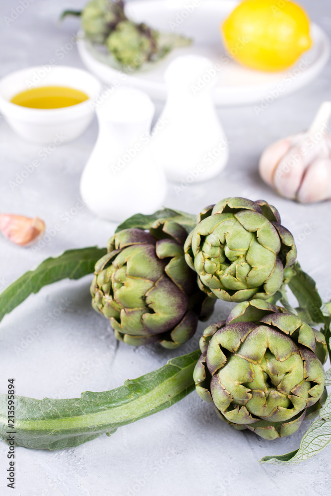 Fototapeta premium Fresh artichoke preparing for cooking with garlic, lemon and olive oil, kitchen interior.