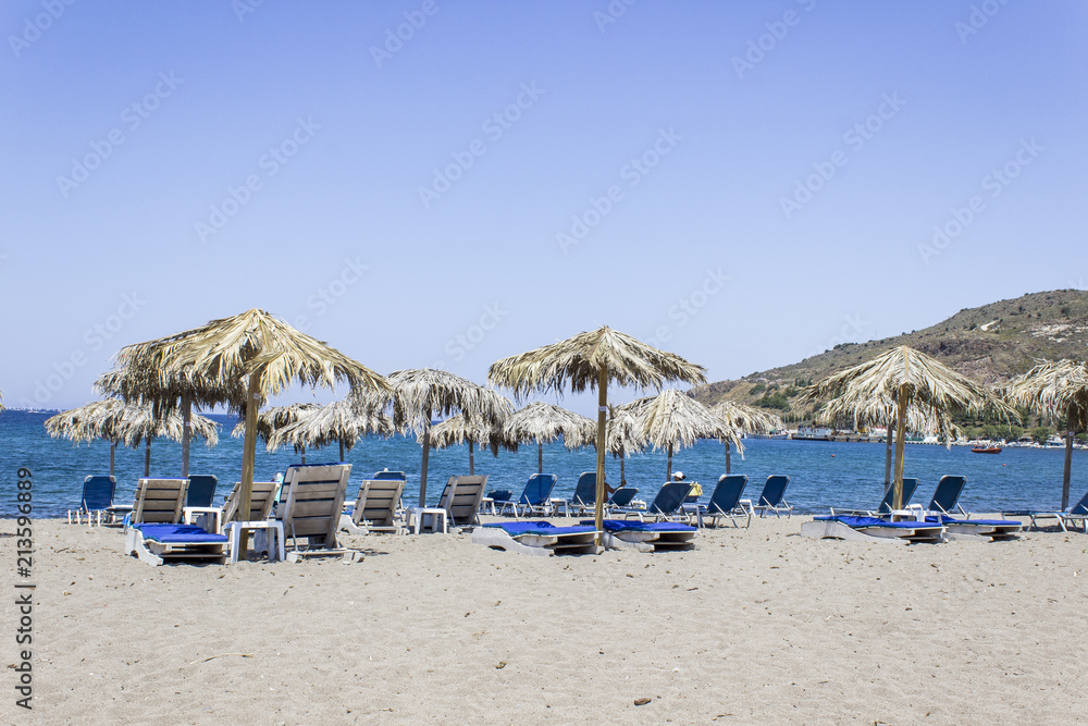 Wide shot of blue sunbeds near open sea at Petra in Lesvos Wide shot of blue sunbeds near open sea at Petra in Lesvos