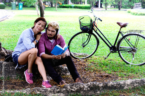 A man read a book and woman read a book too.They are in love and relax time  in public park Thailand.They are honeymoon day. 