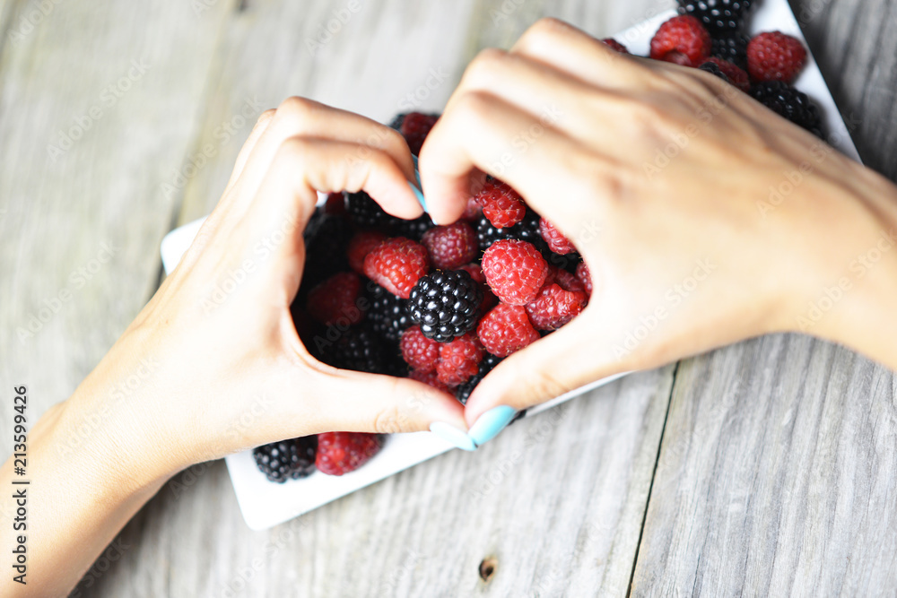 Woman hands in form of a heart over a plate with mixed berries
Woman hands in form of a heart over a plate with mixed berries