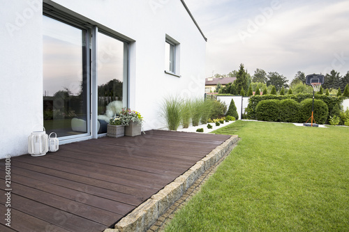 Fotografía Wooden empty terrace of white house with green grass and trees