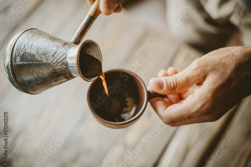 Man pouring hot coffee from turk photo