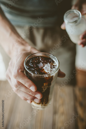 Man pouring milk in iced coffee photo