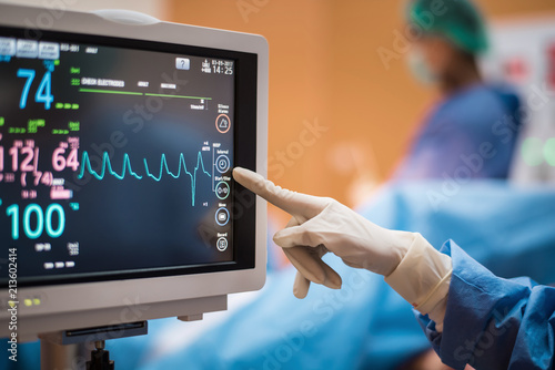 Electrocardiogram in hospital surgery operating  emergency room showing patient heart rate with blur team of surgeons background    photo