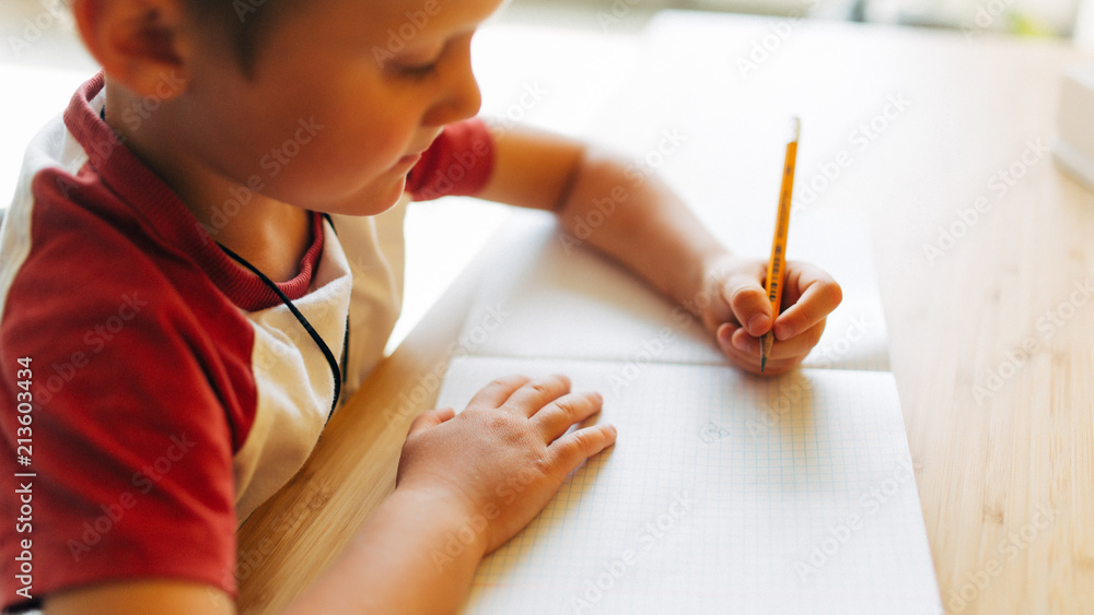 Image of boy with pen and notebook sitting at table Image of boy with pen and notebook sitting at table
