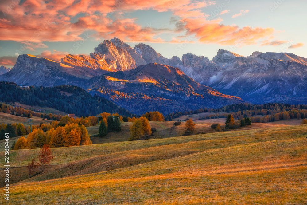 Fototapeta premium Amazing autumn scenery of Alpe di Siusi at sunrise. Majestic mountains and colorful sky in background, Dolomites, Italy