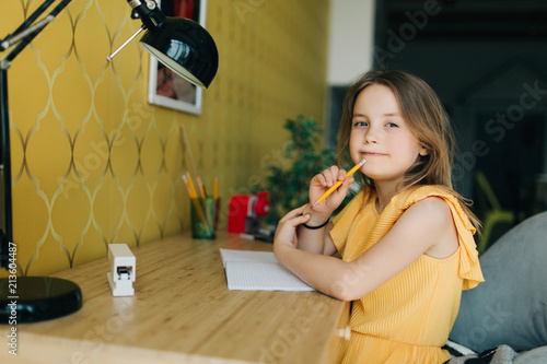 Quadro su tela Photo of girl with pencil and notebook sitting at table