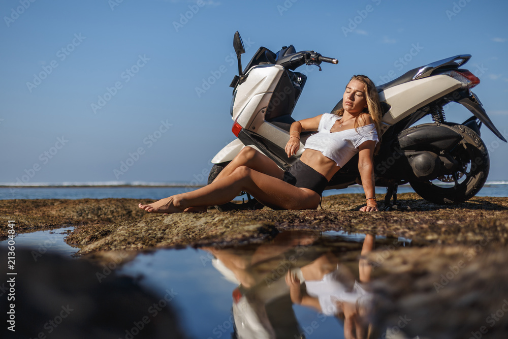 Posing on scooter, young pretty sexy girl outdoor portrait near ocean in  sports wear, jeans, freedom, scooter, bike Stock Photo | Adobe Stock