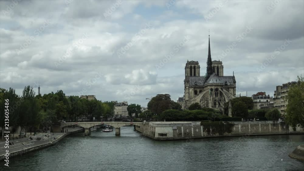 Time lapse of ancient catholic cathedral Notre-Dame de Paris on summer cloudy day. Quays of the Seine river with boats. Water traffic, famous touristic places and popular travel destinations in Europe Time lapse of ancient catholic cathedral Notre-Dame de Paris on summer cloudy day. Quays of the Seine river with boats. Water traffic, famous touristic places and popular travel destinations in Europe