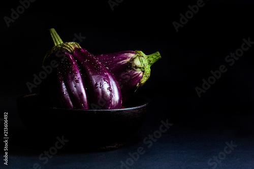 fresh eggplant in wooden cup on black background