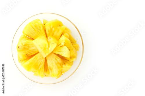 Pineapple slice on a plate placed on a wooden table.