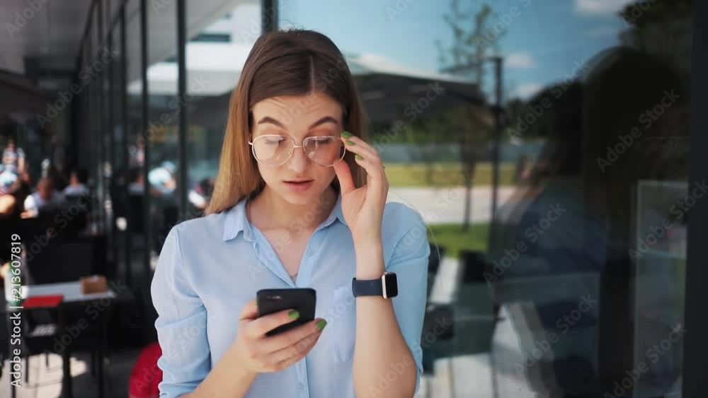 business woman with glasses uses phone wonder stand near business center attractive technology girl internet young digital work screen smart student touch slow motion business woman with glasses uses phone wonder stand near business center attractive technology girl internet young digital work screen smart student touch slow motion