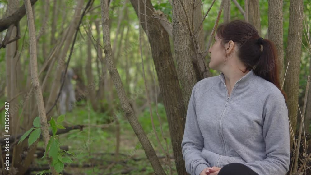 Young brunette woman hiding behind a tree from a man with an ax. Young brunette woman hiding behind a tree from a man with an ax.