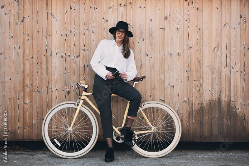 Woman sitting on the yellow bicycle and using smart phone for texting.