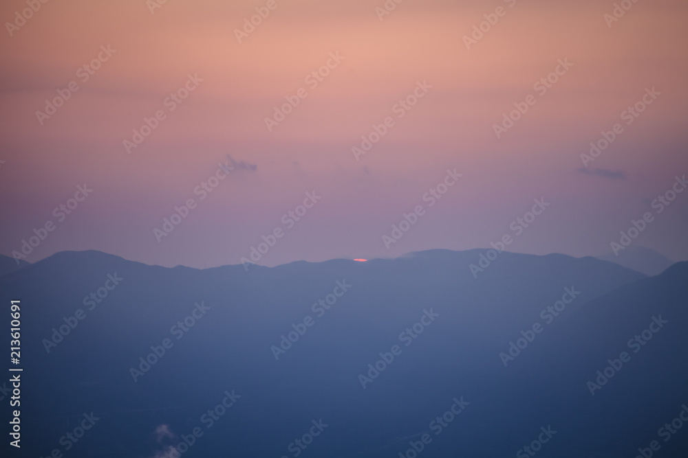 A pastel sunset panorama of mountains in the winter.
