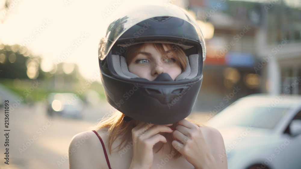 Fototapeta premium beautiful young red-haired woman motorcyclist with black motorcycle helmet