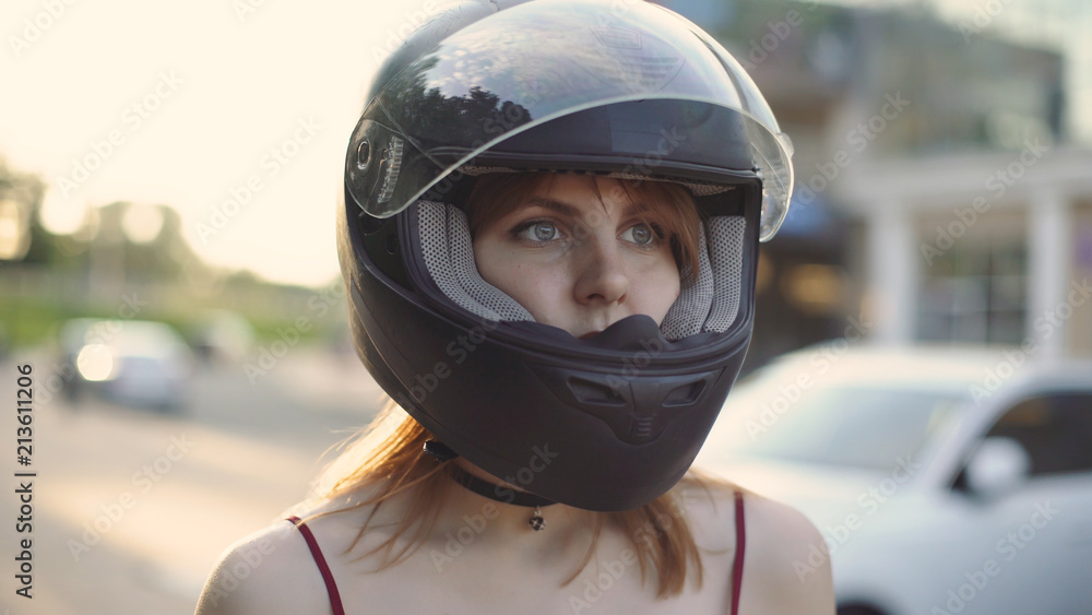 beautiful young red-haired woman motorcyclist with black motorcycle helmet