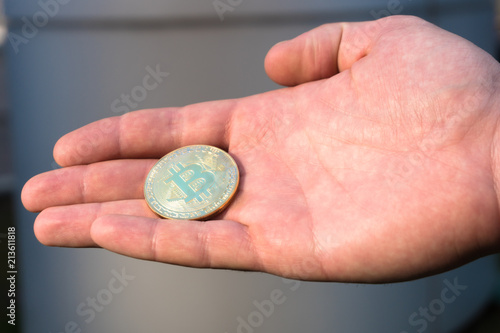 The man stretches a bitcoin, bitcoin in the hand, open palm with bitcoin