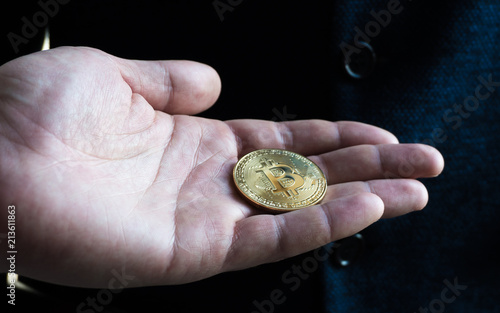 The man stretches a bitcoin, bitcoin in the hand, open palm with bitcoin