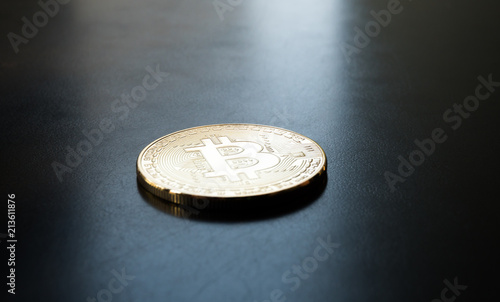 Bitcoin on a black background, golden coin lying on the black table, isolated