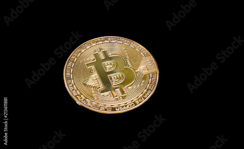 Bitcoin on a black background, golden coin lying on the black table, isolated