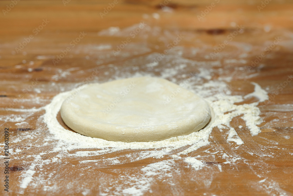 Pizza dough. Basis for baking pizza on a wooden table, close-up Pizza dough. Basis for baking pizza on a wooden table, close-up