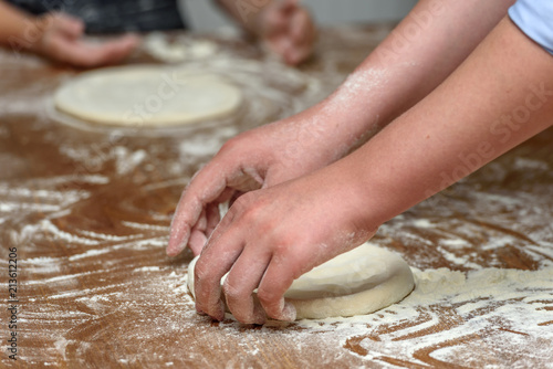 Close-up of children's hands preparing dough for pizza