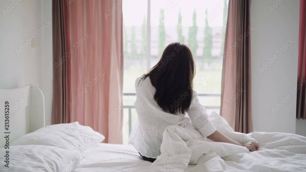 Happy asian woman waking up and stretching arms on bed at morning. Happy asian woman waking up and stretching arms on bed at morning.