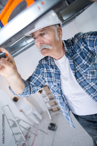 man making mount for electrical wires on ceiling