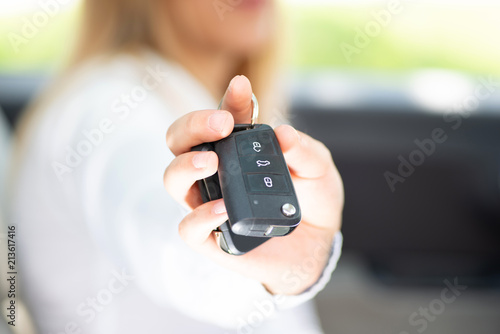 Junge Frau freut sich über ihr Auto und hält die Autoschlüssel in der Hand 