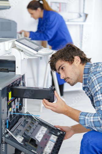 male technician repairing digital photocopier machine