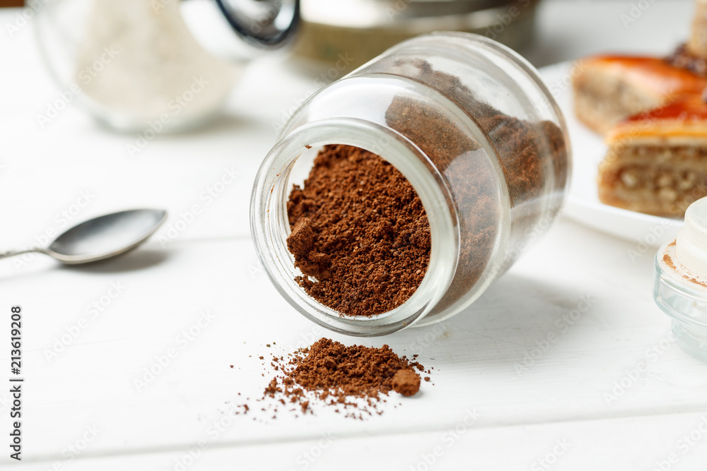 Ground natural coffee in glass jar on a white table Ground natural coffee in glass jar on a white table