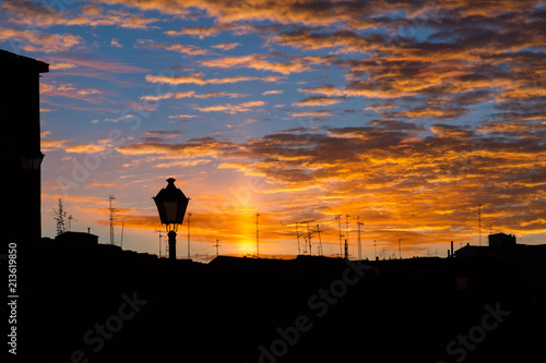 Bello cielo de amanecer sobre los tejados de la ciudad antigua con antenas de Tv y chimeneas a contraluz