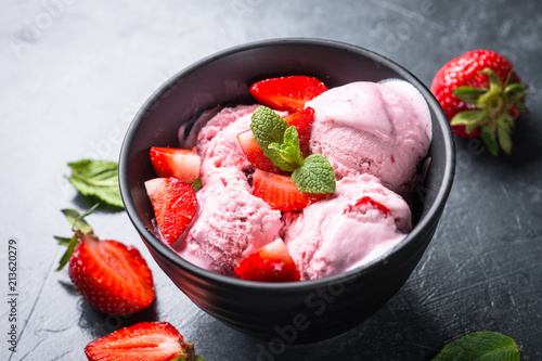 Strawberry ice cream in black bowl.