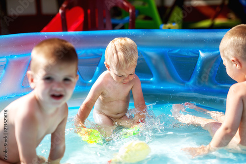 Baby kids playing at baby pool at backyard. Kids pool having fun. Summer day at home. Family time.