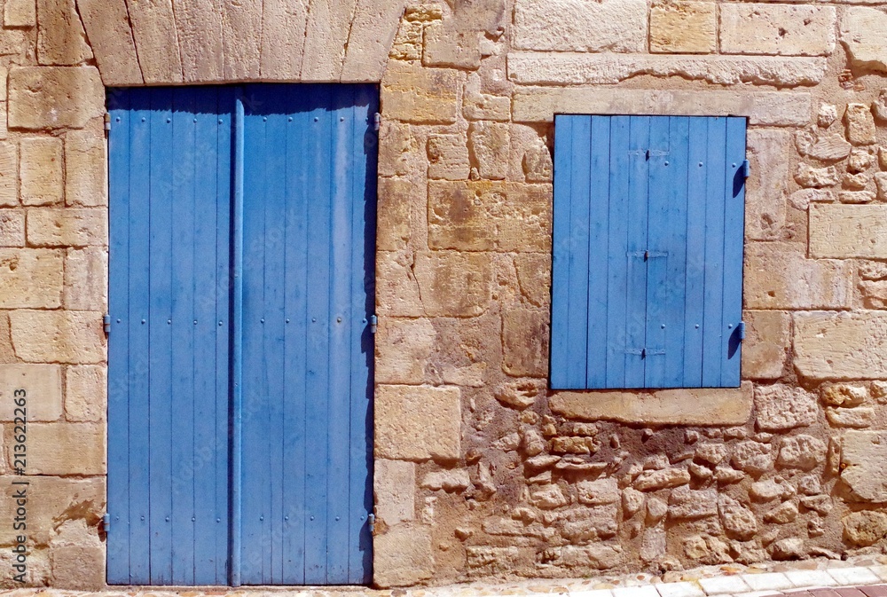 Exterior detail of a traditional stone cottage with closed blue window and door.
