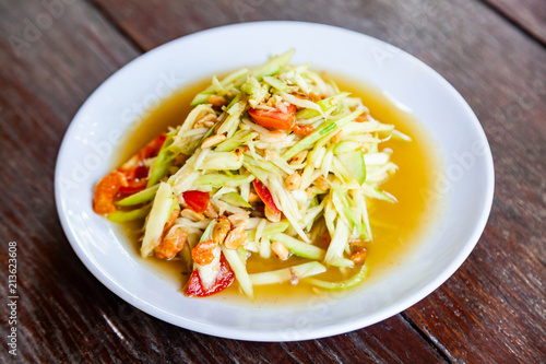 Papaya Salad on Wood Table, Thai cuisine Som Tam a famous Thai food, Thai Salad, sweet, salty, tangy, and spicy flavor.
