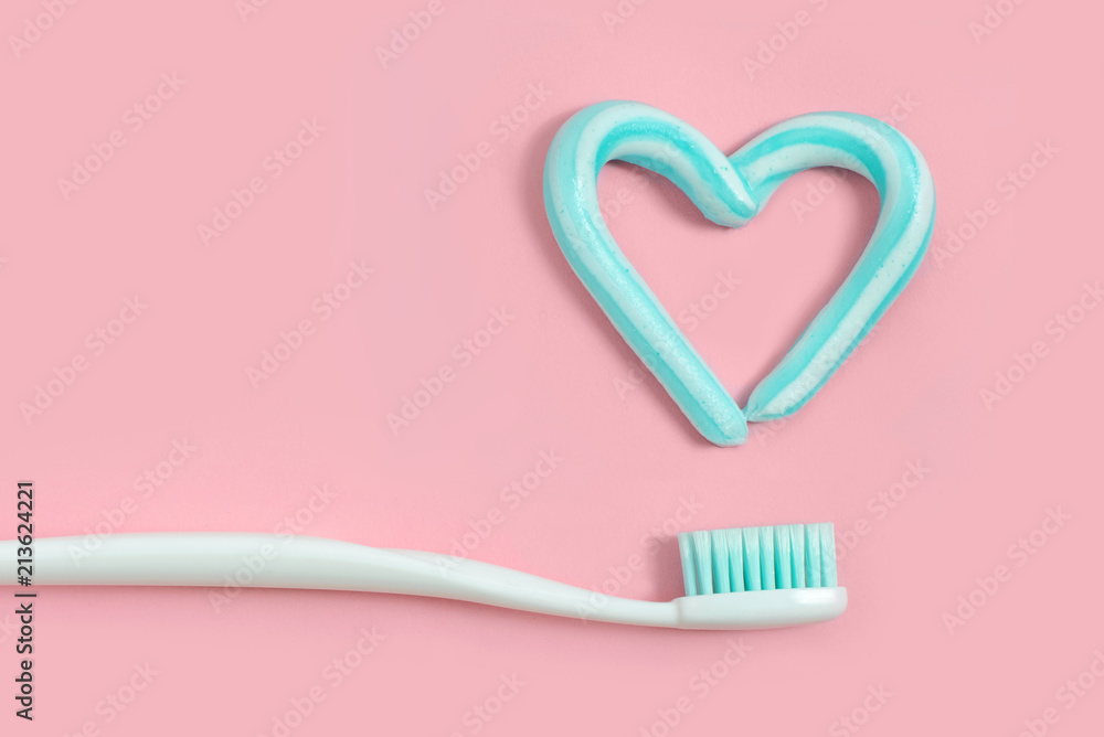 Toothbrushes and turquoise color toothpaste in shape of heart on pink background. Dental and healthcare concept. Toothbrushes and turquoise color toothpaste in shape of heart on pink background. Dental and healthcare concept.