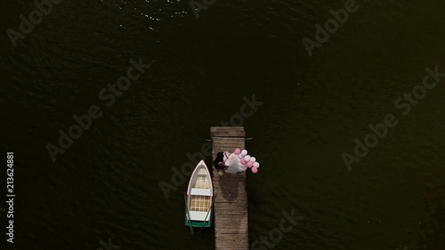 Young wedding couple is standing on a small bridge near beautiful lake.