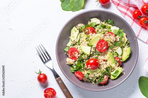 Quinoa salad with spinach, avocado and tomatoes top view.
